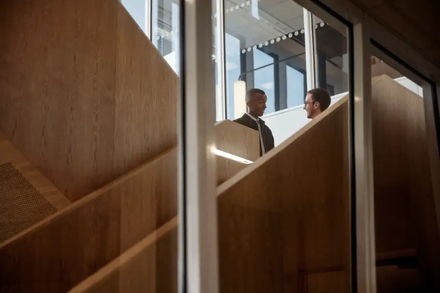 Två kollegor står och pratar i kontorsmiljö.