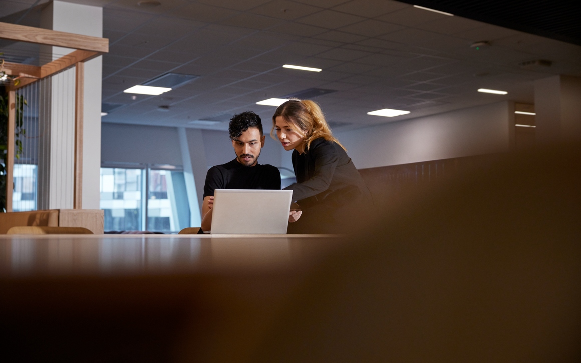 En man och en kvinna framför en laptop i kontorsmiljö.