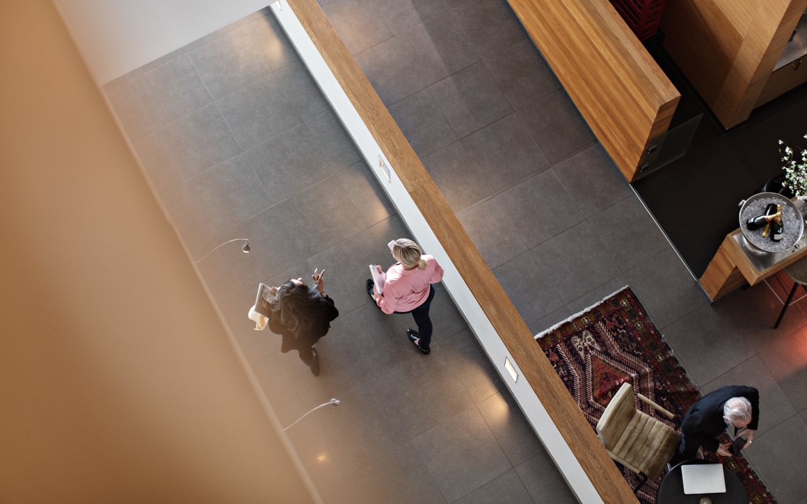 Hög vinkelvy av kvinnliga kollegor som diskuterar medan de går i en korridor på kontoret