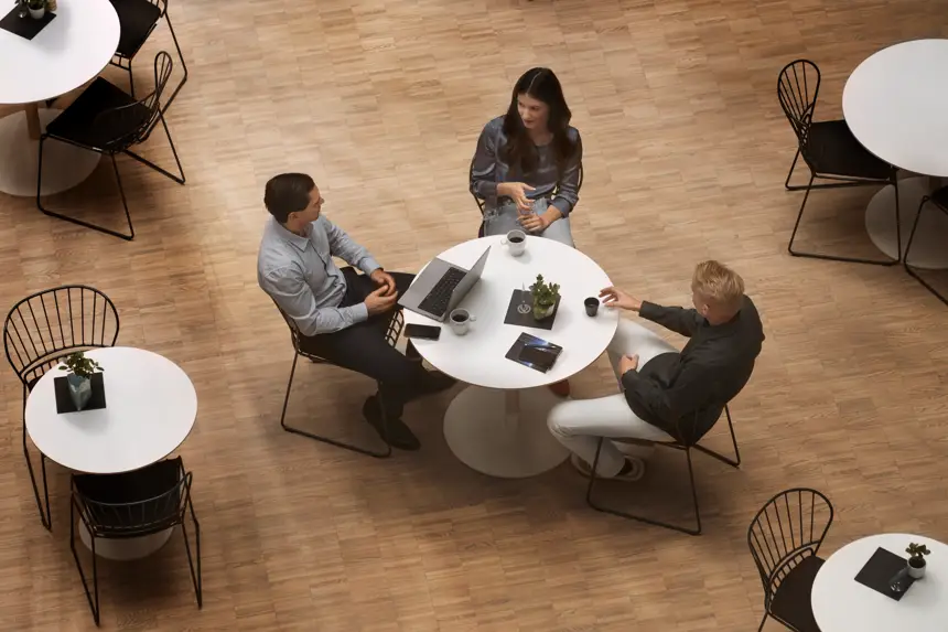 Tre personer sitter runt ett bord med uppfälld dator på.