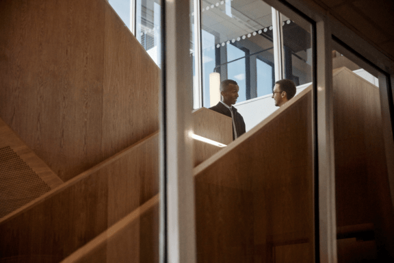 Två kollegor står och pratar i kontorsmiljö.